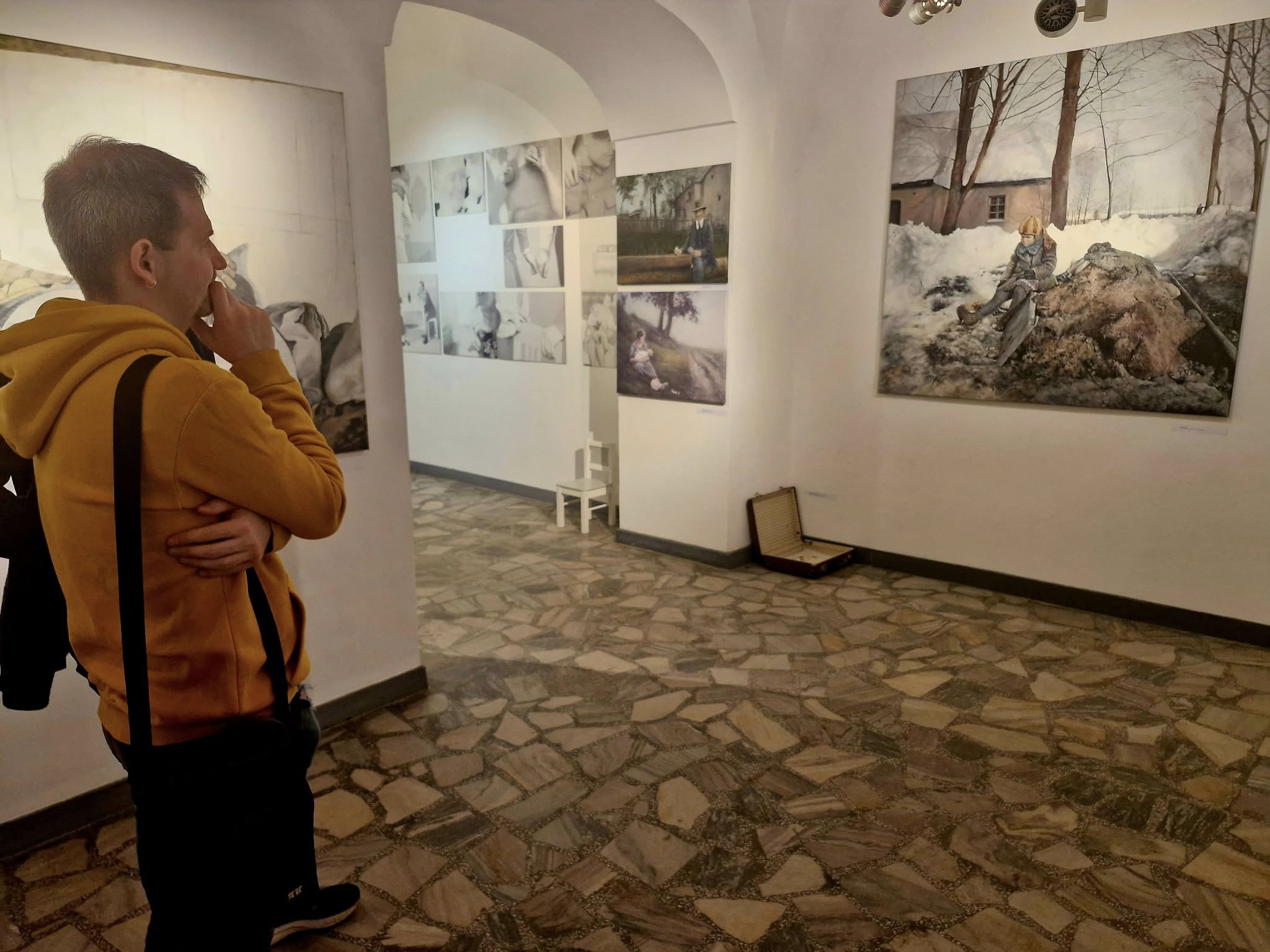 zdjęcie galerii w Zamku w Leśnicy, mężczyna ogląda wiszący na ścianie obraz z postacią na tle ośnieżonego domu